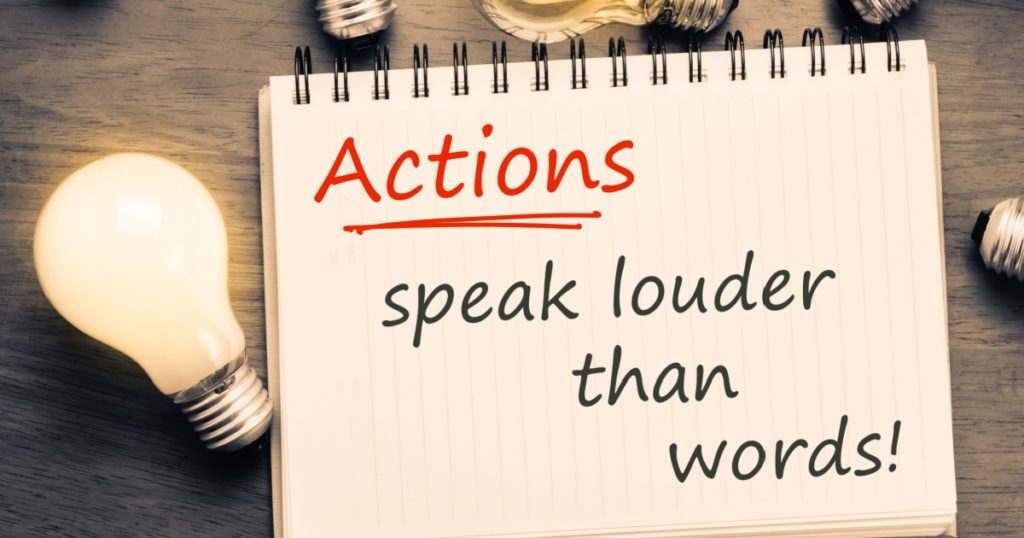Actions Speak Louder Than Words text on notebook with many light bulbs