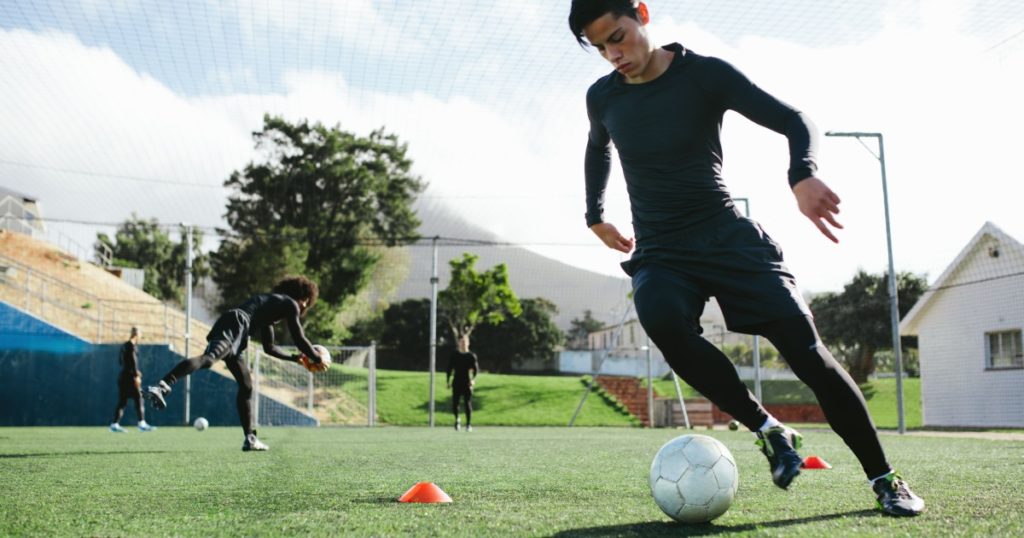 Football player training in soccer field. Young soccer player practicing ball control on training session.