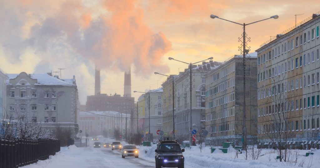 Northern industrial city. Sunset. Smoke from the chimney is visible above the houses. Bogdan Khmelnitsky Street. Norilsk, Krasnoyarsk region, Siberia, Russia.