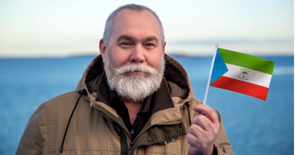 Man holding Equatorial Guinea flag. Portrait of older man with a Equatorial Guinea flag. Visit Equatorial Guinea concept. Older man 50 55 60 years old with gray beard outdoors travelling in winter.
