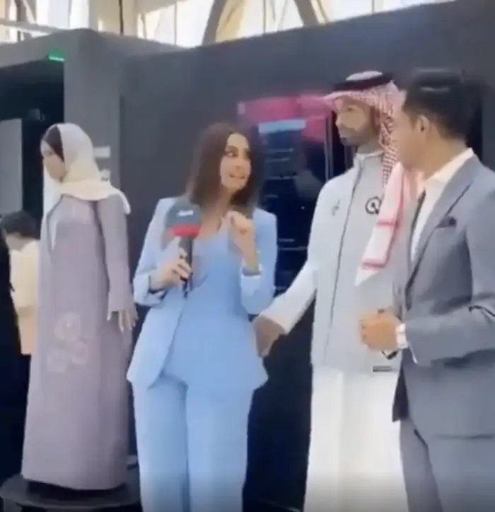 A male robot touching a female reporter's buttocks.