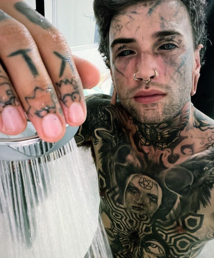 Man with tattoos in shower.
