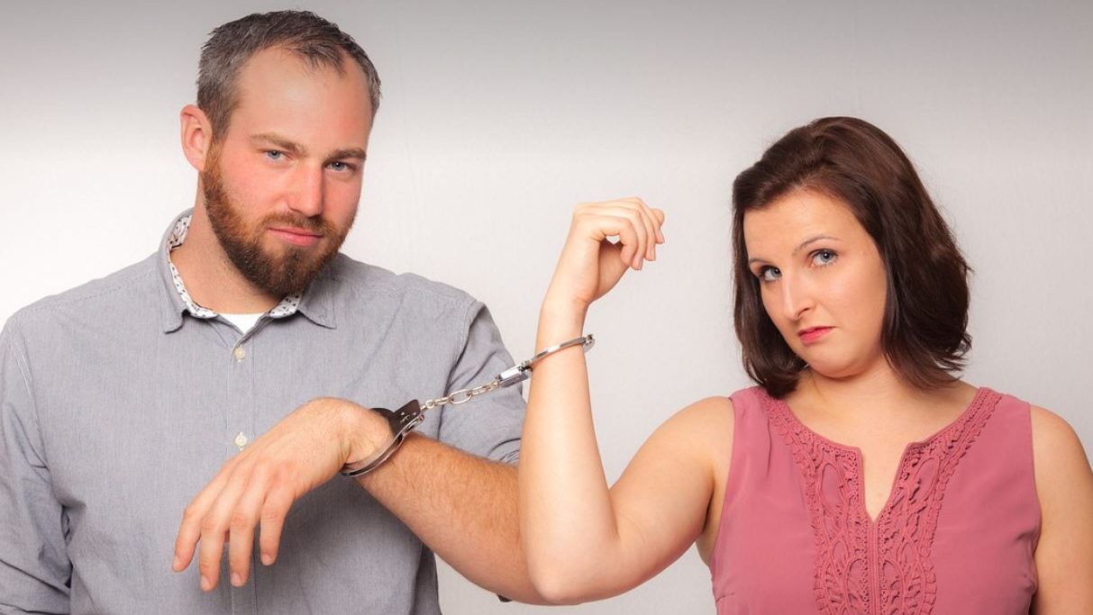 Man and woman handcuffed to each other. White background. 