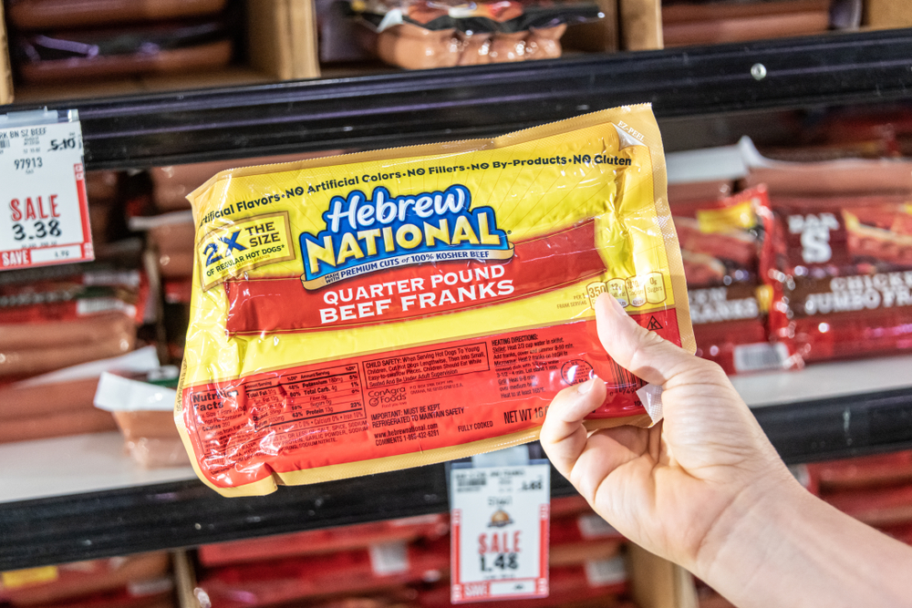 Sacramento, CA/USA 06/07/2019 Shoppers hand holding a package of Hebrew National brand quarter pound beef franks in a supermarket aisle
