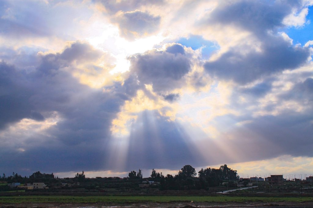 Green landscape with some buildings. Sunlight shining through the clouds. 