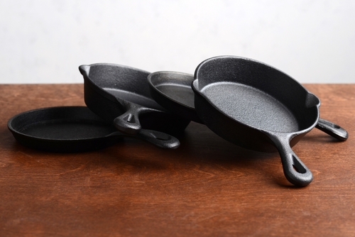 pile of cast iron skillets on old wood table