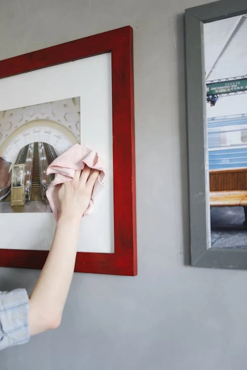 A Person Wiping the Frames Hanging on the Wall