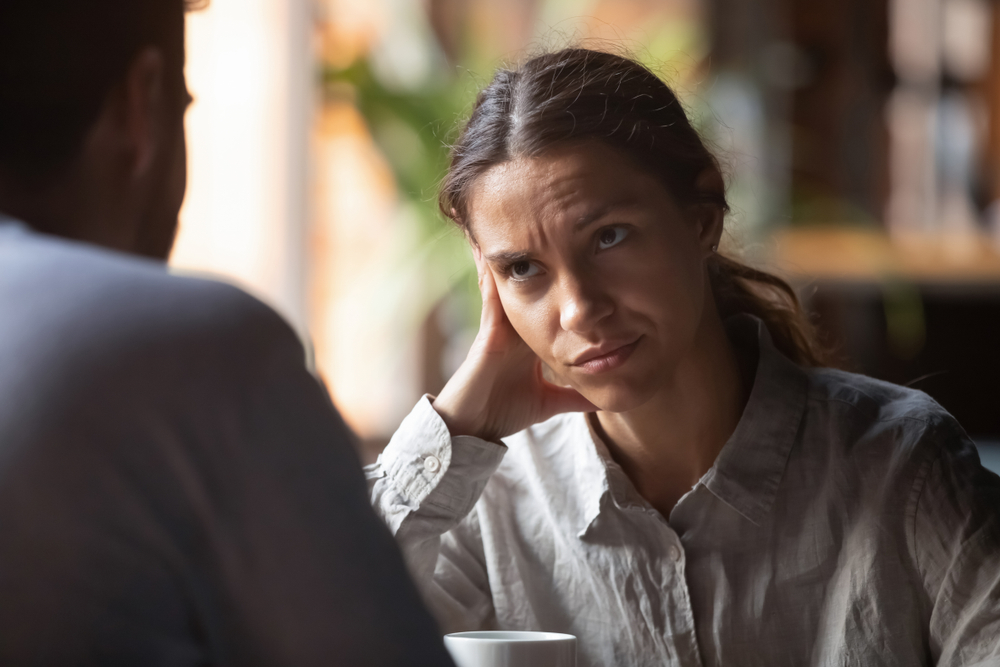 Focus on multiracial irritated young female sitting in cafeteria on speed dating with boring male rear view. Unsuccessful unlucky romantic date failure bad first impression and poor companion concept