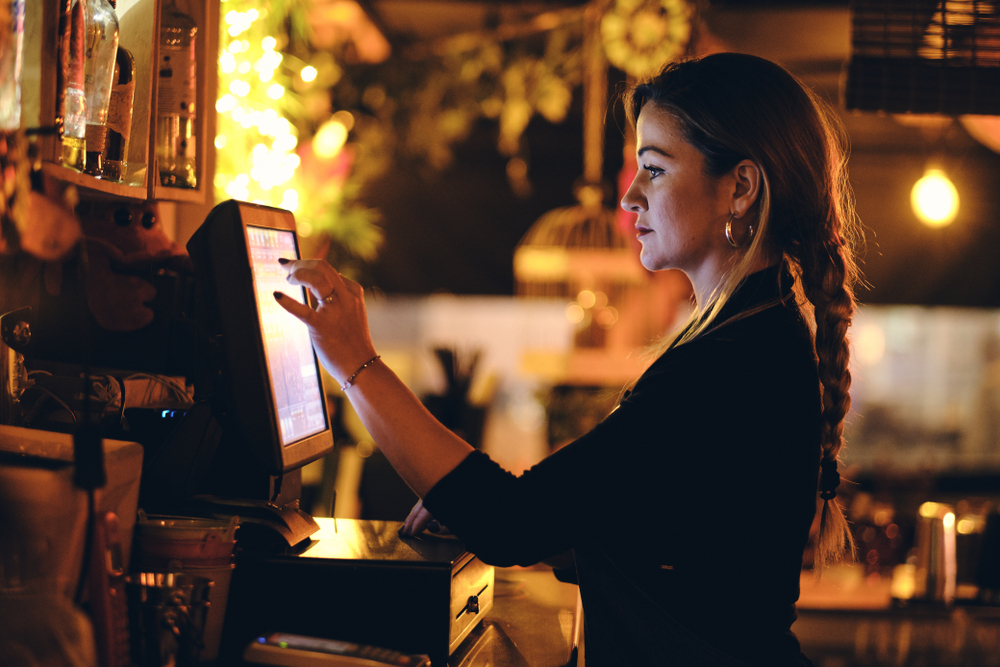 small business, people and service concept - A young waitress at counter in a small bar or restaurant