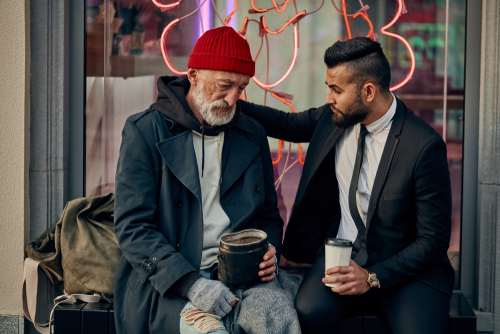 Rich man in tuxedo and homeless person in dirty clothes sitting and talking in the street. Poverty, help