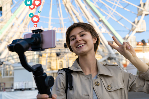 Millennial hipster teen girl blogger influencer record vlog on smart phone holf selfie stick. Travel vlogger shoot video blog instagram story,streaming on urban city street get likes and hearts emoji.