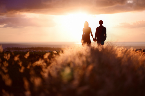Young couple enjoying the sunset in the meadow