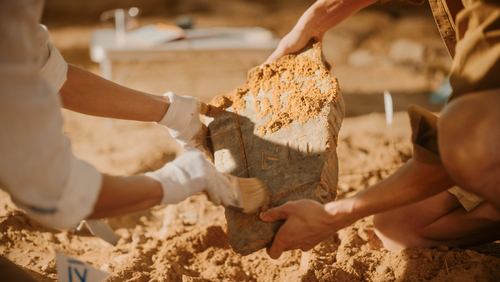 Archeological Digging Site: Two Great Archeologists Work on Excavation Site, Carefully Cleaning, Holding Newly Discovered Ancient Civilization Cultural Artifact, Historic Clay Tablet, Fossil Remains