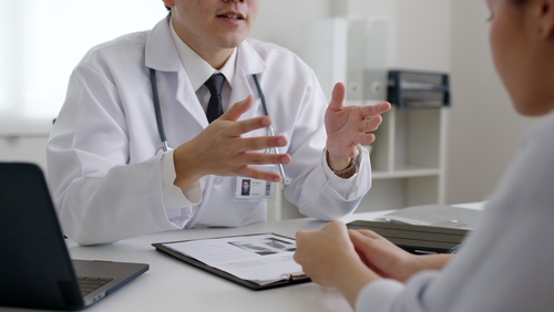 Friendly medic service people or asia male help talk discuss of medical exam record test result at clinic office desk. Young sad serious stress woman visit, follow , listen, see doctor at hospital.