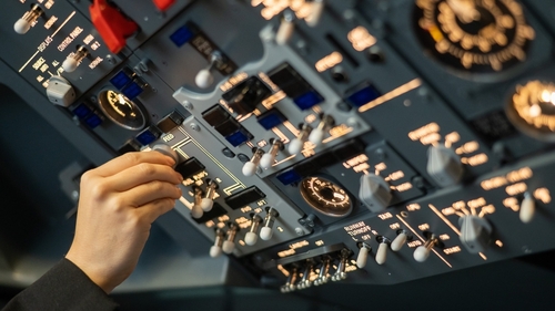 Close-up of a pilot's hand turning a toggle switch on the control panel.