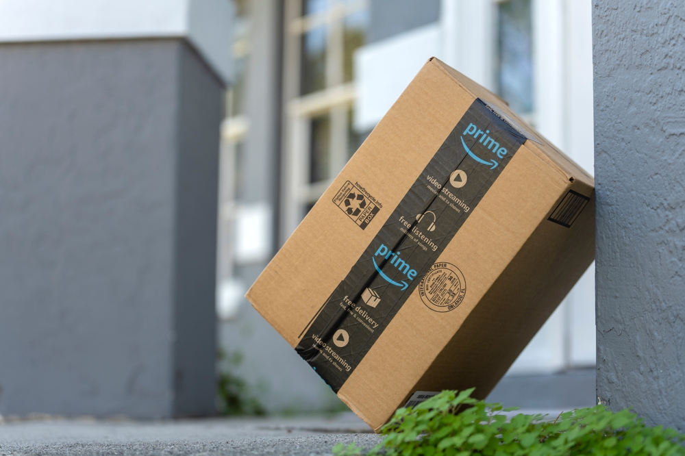 Amazon Prime package box with purchased online products delivered in front of house door. Amazon Prime priority delivery. E-commerce concept. Sarasota, USA - December 19, 2022.