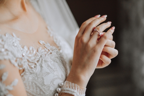 The bride is holding a gold ring in her hands, close-up. Morning of the bride. Wedding day. Beautiful lace dress. Sexy girl