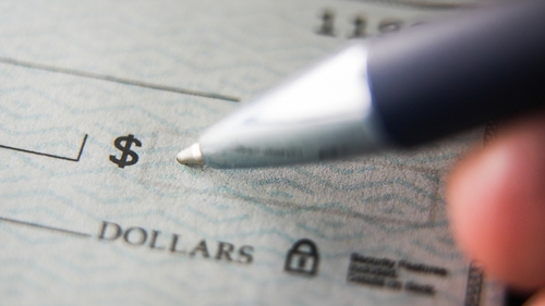 Close up view of a pen ready to sign a blank check on a desk