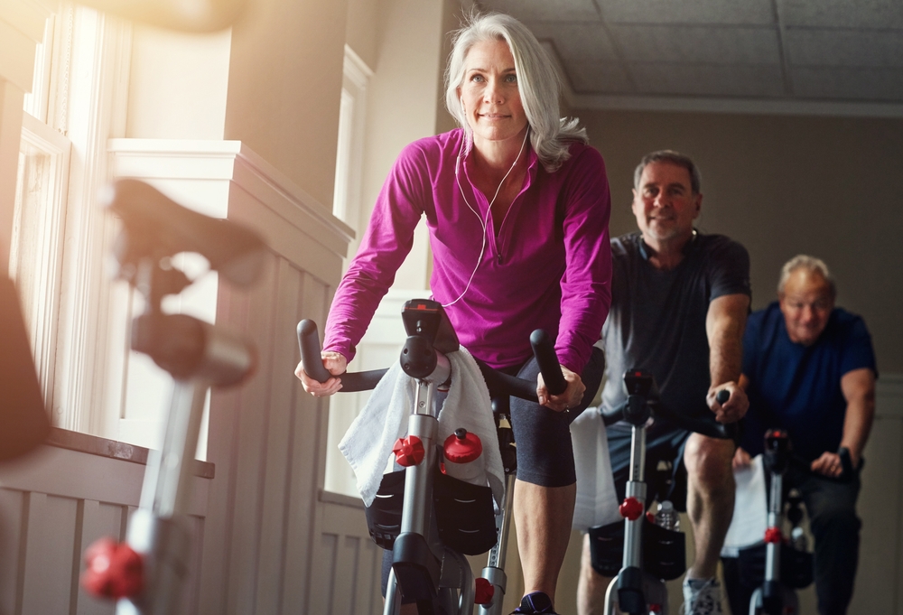 Fitness, spinning class and senior people in gym for cycling, exercise and training with physical activity. Workout club, men and woman on bicycle for health, wellness and endurance with cardio