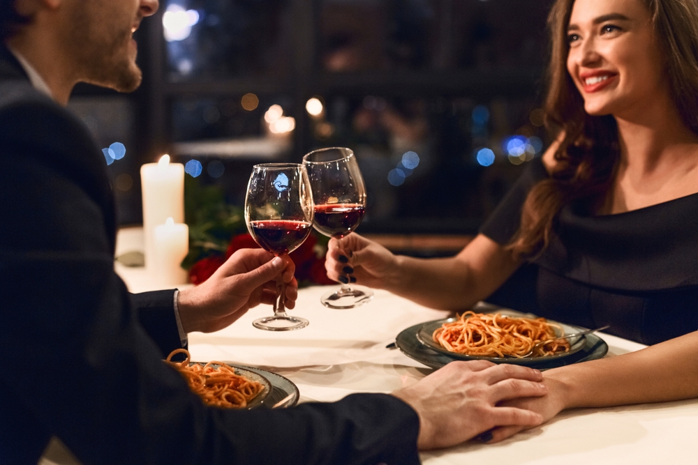 Happy couple having romantic dinner in restaurant, eating pasta and drinking red wine. Happy Valentine day concept