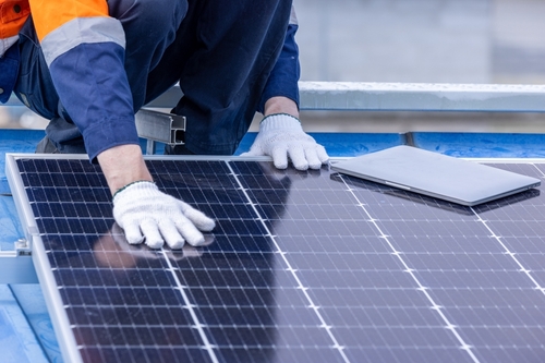 Male professional engineer installing solar photovoltaic panel system, Electrician, worker mounting blue solar module technology on power industrial factory roof, Alternative energy, renewable energy.