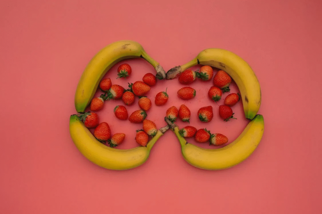 Yellow Bananas and Strawberries on Pink Surface