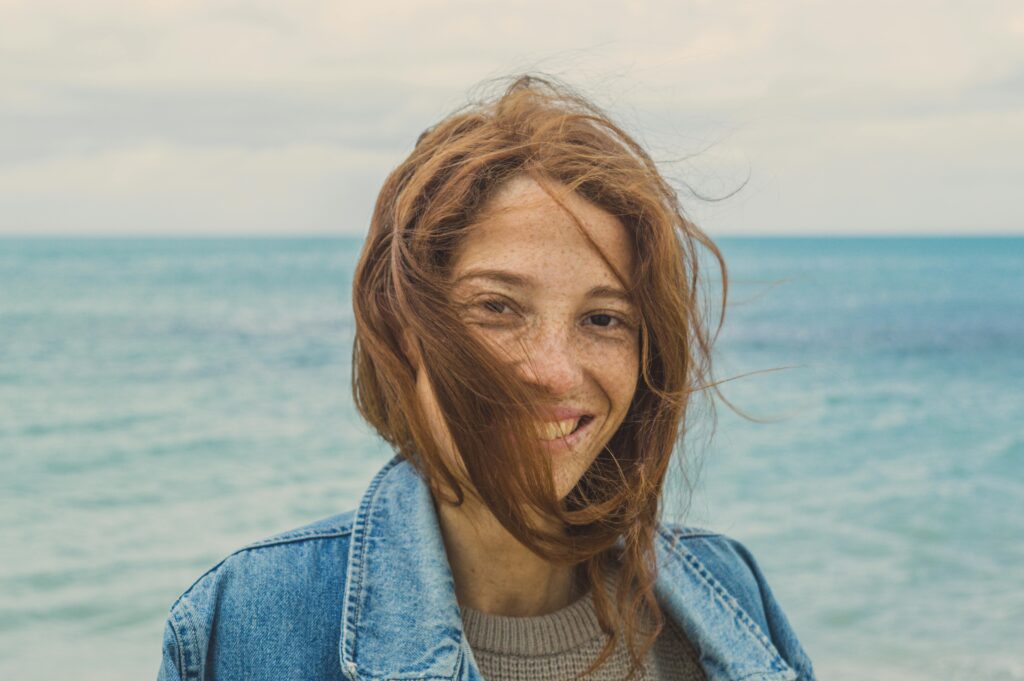 Portrait Photo of Smiling Woman with brown Hair Near Body of Water