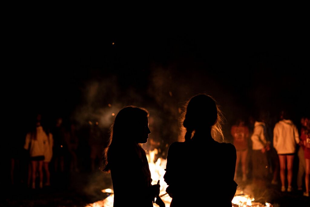 Silhouette of Two Women Standing in Front of Bonfire during Nighttime