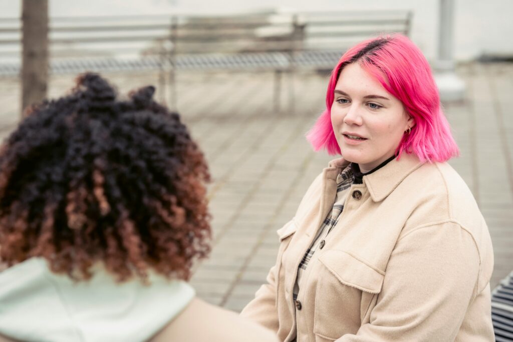 woman with pink hair talking to another woman 