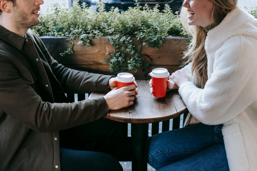 Crop couple with takeaway cups on terrace