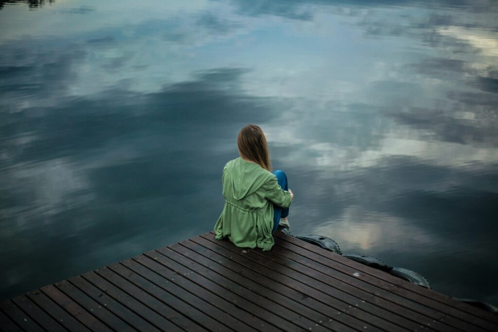 woman sitting alone at water