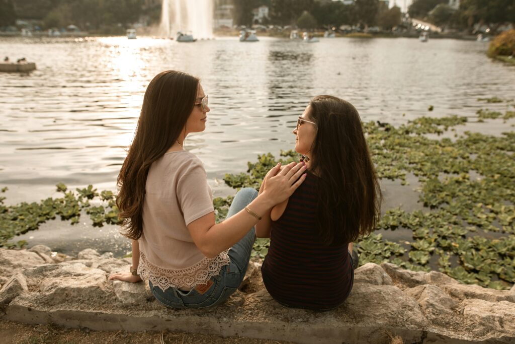 two woman sitting by the lake