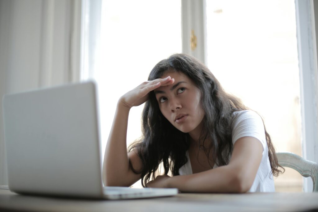 Young annoyed female freelancer using laptop at home