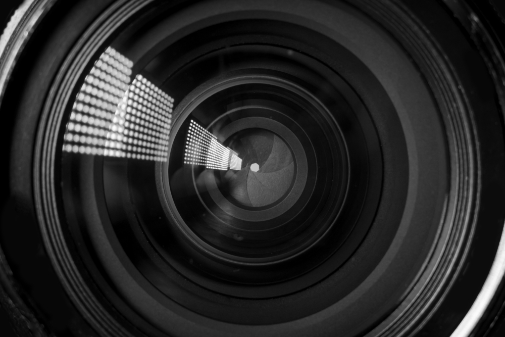 Photo Camera or Video lens close-up on black background, objective, concept of photographer camera man job, looking for a photographer, journalist, a videographer to work black and white