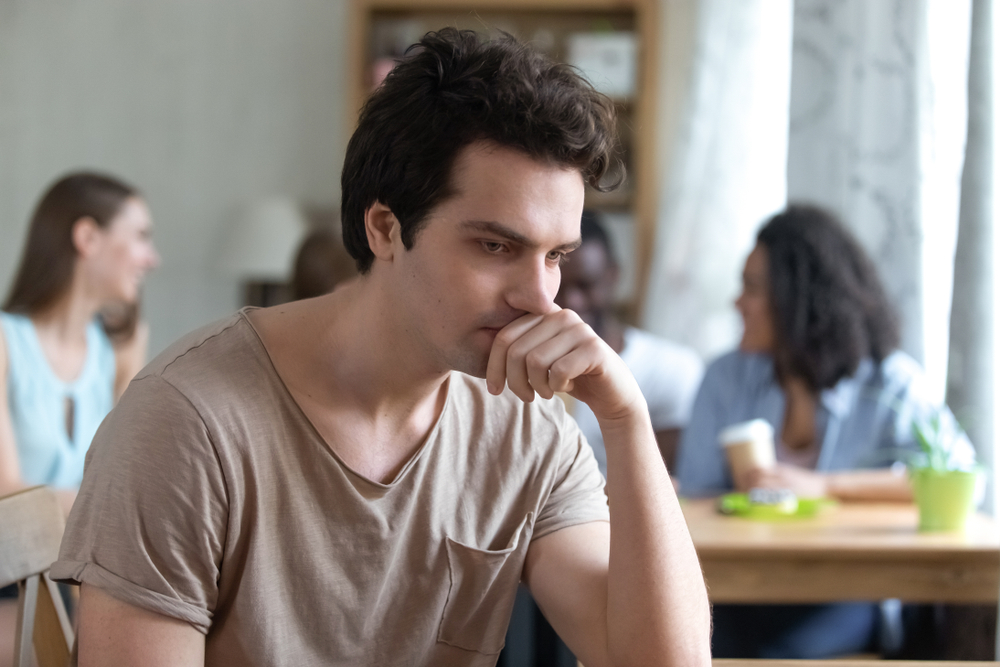Upset thoughtful man sitting alone low self-esteem have no friends feeling depressed outsider Upset multiracial woman offended by friends feeling unhappy concept suffering from bullyin