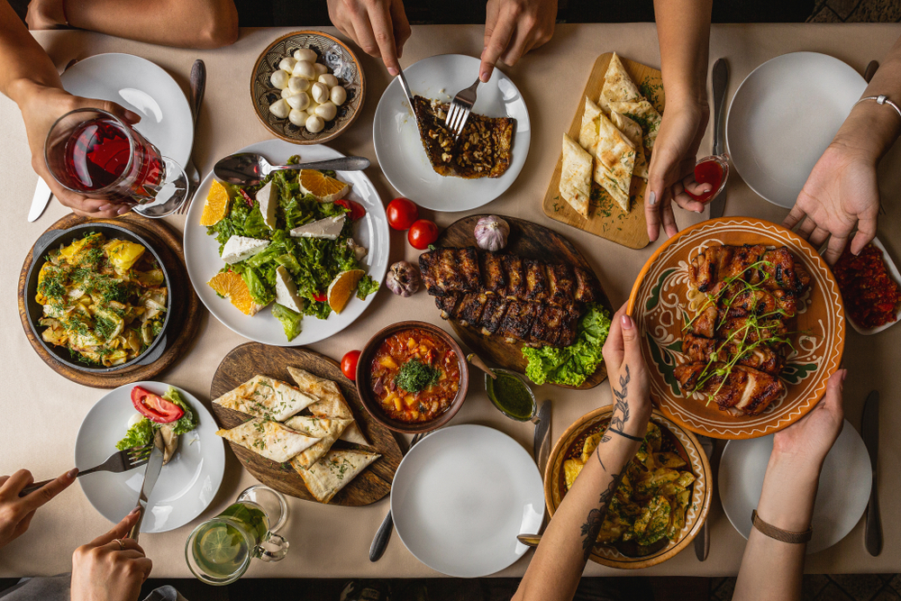 large and generously covered with delicious dishes table, covered with a tablecloth on which there are various delicious dishes of Ukrainian cuisine: fried ribs, borsch, salads, cheese