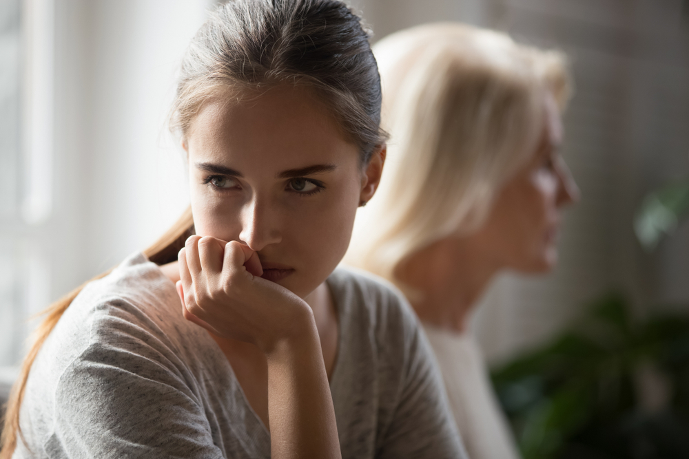 Offended millennial adult daughter and senior mother sit aside back to back avoid talking after fight, hurt stubborn two generations of women ignore each other after conflict, misunderstanding concept