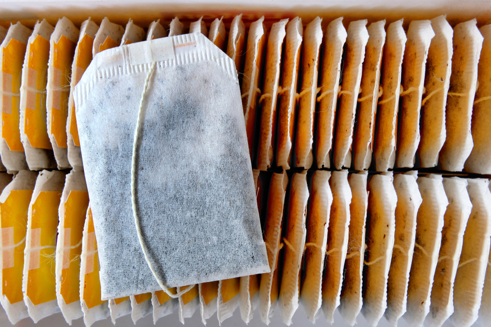 A tea bag lying on top of rows of other neatly arranged teabags inside a recently opened tea box. A choice selection of teabags for a morning drink and a refreshing afternoon break.