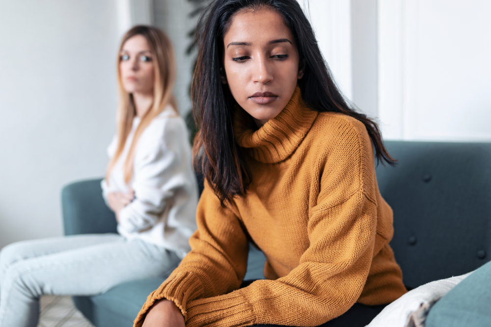Shot of two upset friends not talking to each other after fight on the sofa at home.