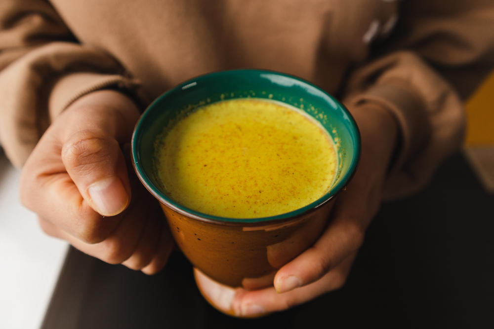 woman hnolding cup of golden milk