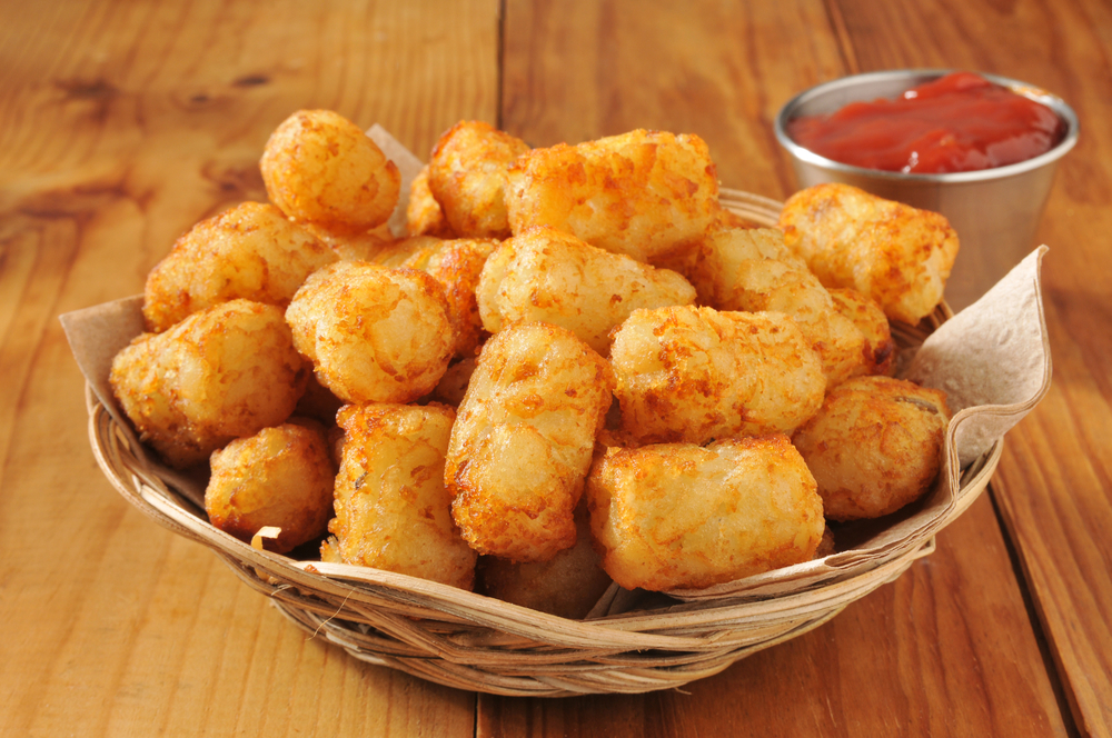 A basket of tater tots on a rustic wooden counter