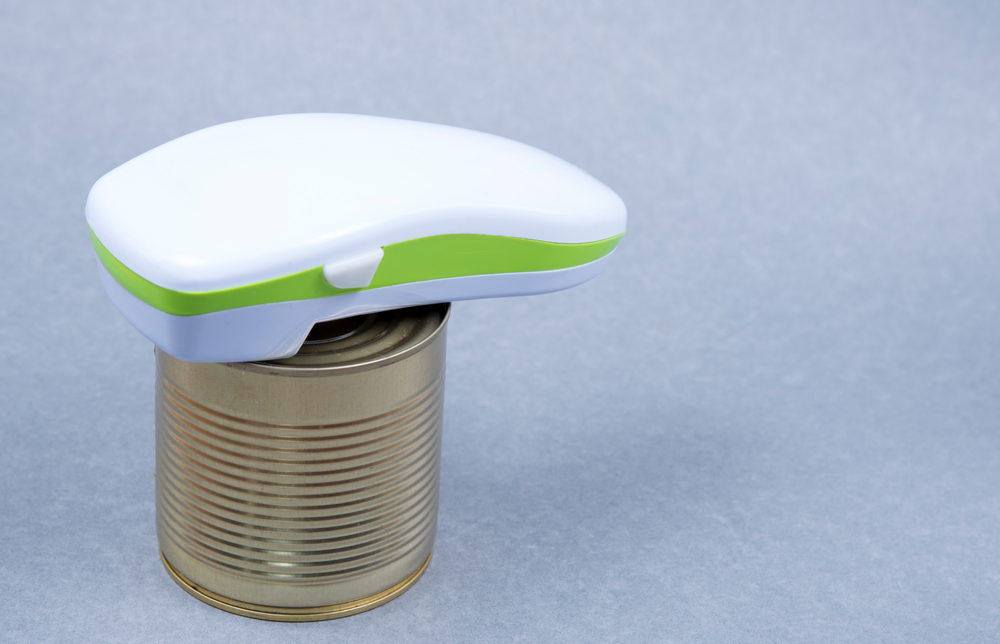 Electric can opener and canned good isolated on gray background