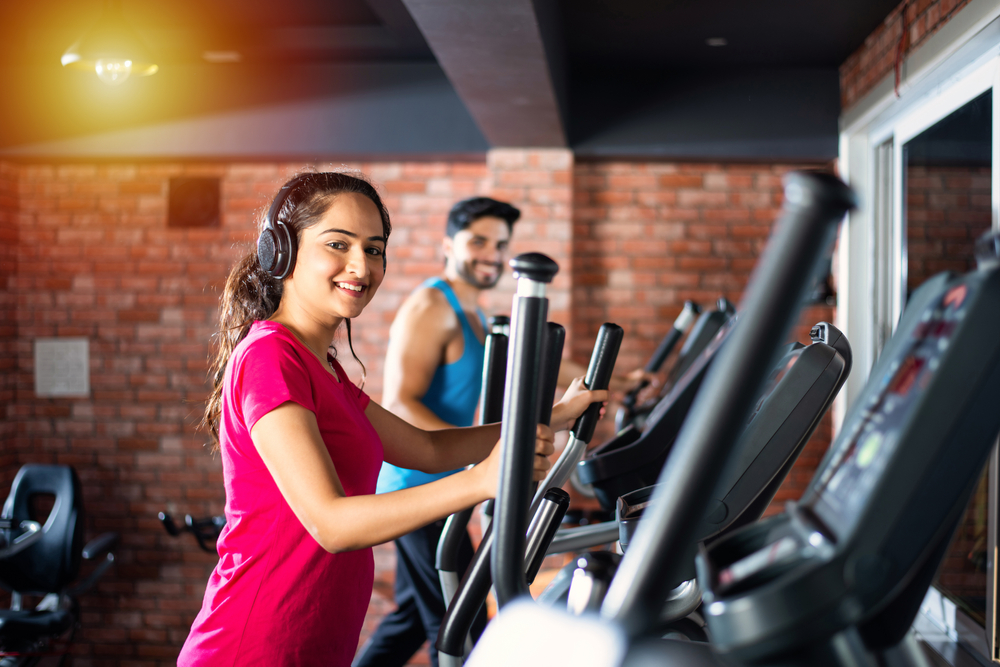 Indian asian attractive couple doing cardio training program in fitness center or gym, selective focys - health and fitness concept