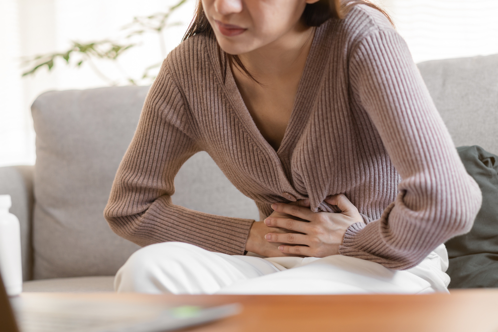 Flatulence young asian woman, girl hand in stomach ache, suffer from food poisoning, abdominal pain and colon problem, gastritis or diarrhoea. Patient belly, abdomen or inflammation, concept.