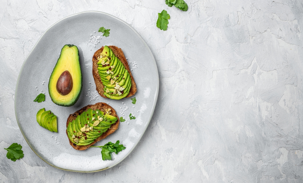 Healthy avocado toasts for breakfast or lunch with rye bread, sliced avocado, pumpkin seeds, salt and pepper. Vegetarian food. Plant-based diet. Clean eating. Top view. Copy space,
