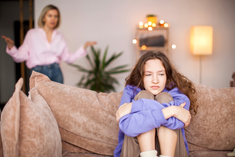 Conflict between mother and child. Woman screams at teenage girl. Sad child feels resentment and hopelessness. Abuse