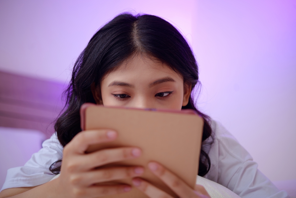 College student reading captivating book or article on tablet computer