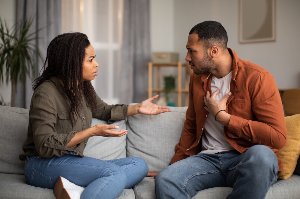 Angry Black Couple Having Quarrel Experiencing Crisis In Relationship Sitting On Sofa At Home. Spouses Having Conflict Breaking Up. Marital Problems, Divorce Concept
