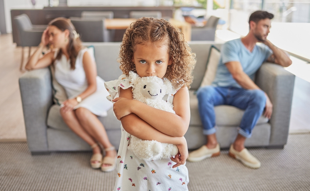 Sad girl, fighting parents thinking of divorce in living room and child scared family will separate. Depressed toxic home worry kid with support needs, upset mother and frustrated father in argument