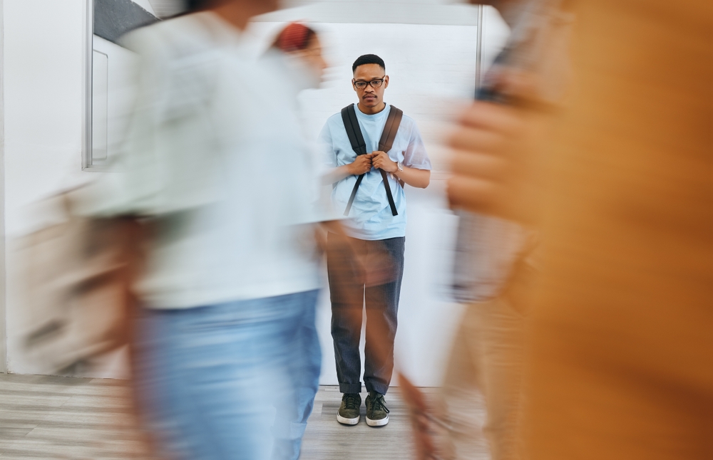 Bullying, depression and sad university student, black man and mental health problems in busy college. Social anxiety, depressed and lonely campus guy, loser and victim fail in school youth education